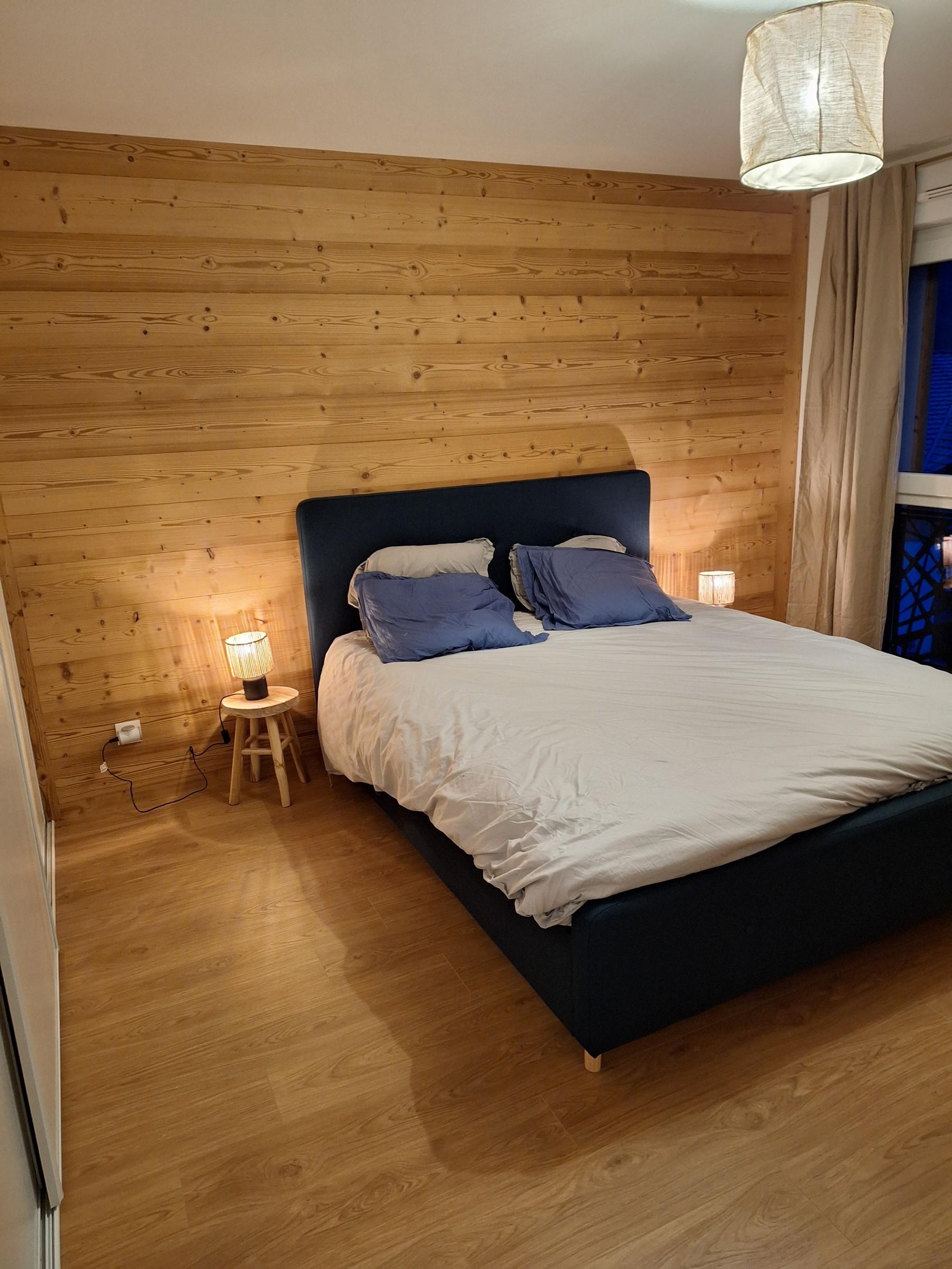 Chambre rénovée avec tête de lit en bois, par Aravis Menuiserie
