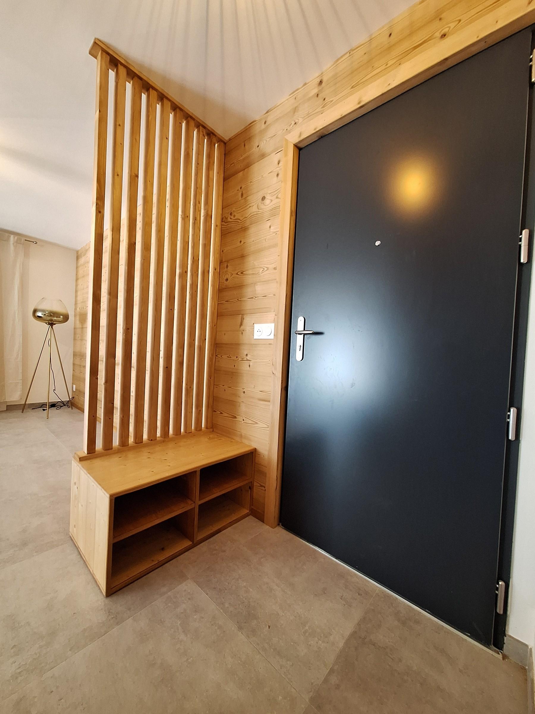 Entrée avec claustra et banc en bois, réalisés par Aravis Menuiserie