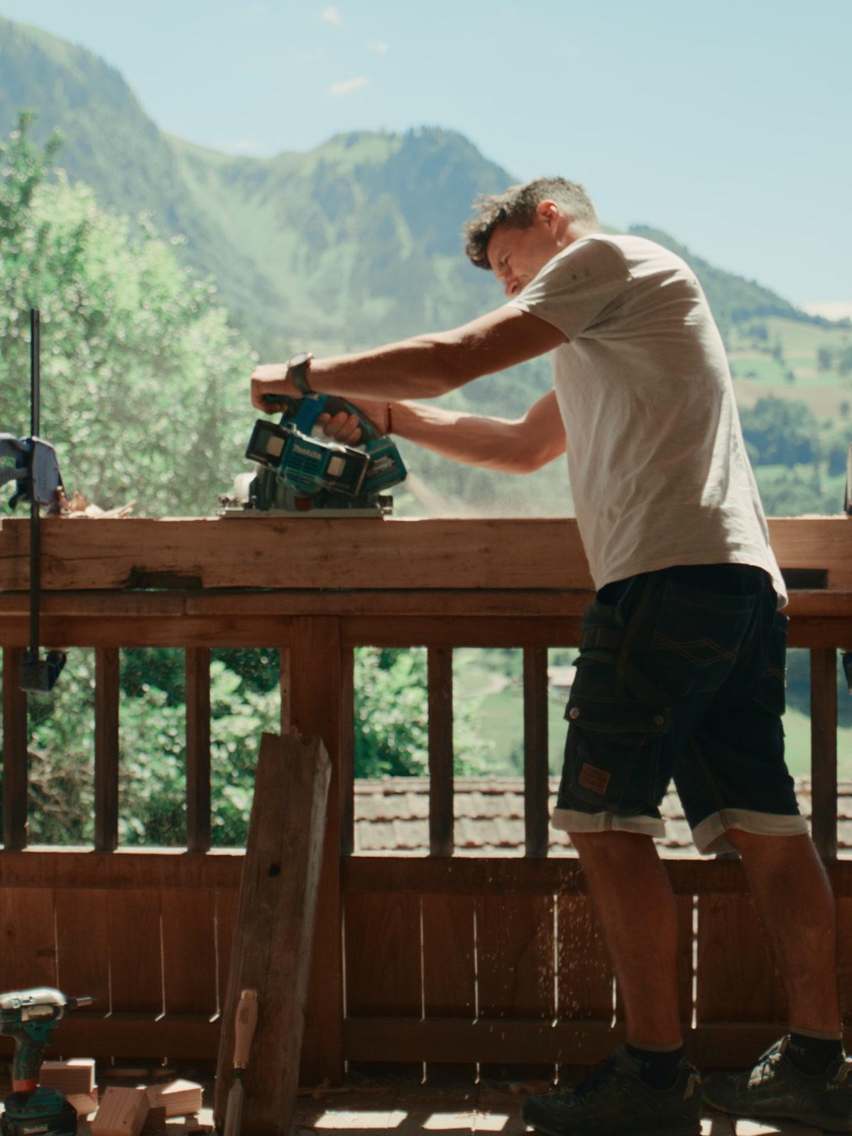 Artisan d'Aravis Menuiserie travaillant sur un balcon face aux montagnes