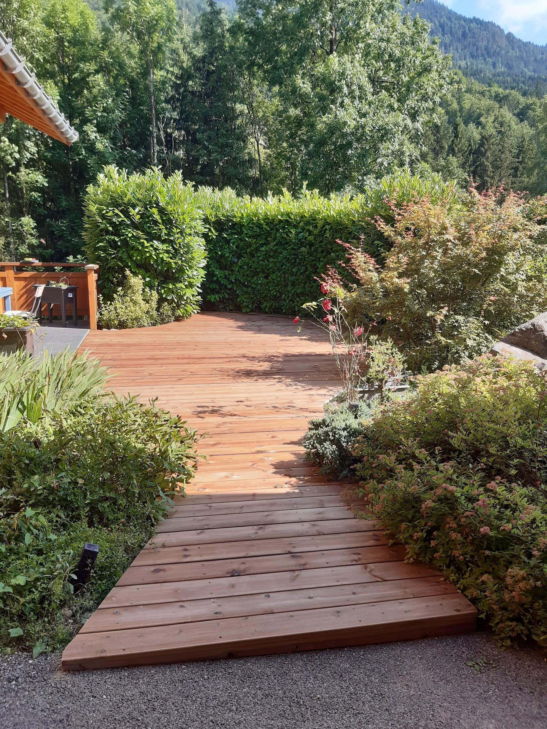 Passerelle et terrasse en bois dans un jardin, réalisées par Aravis Menuiserie