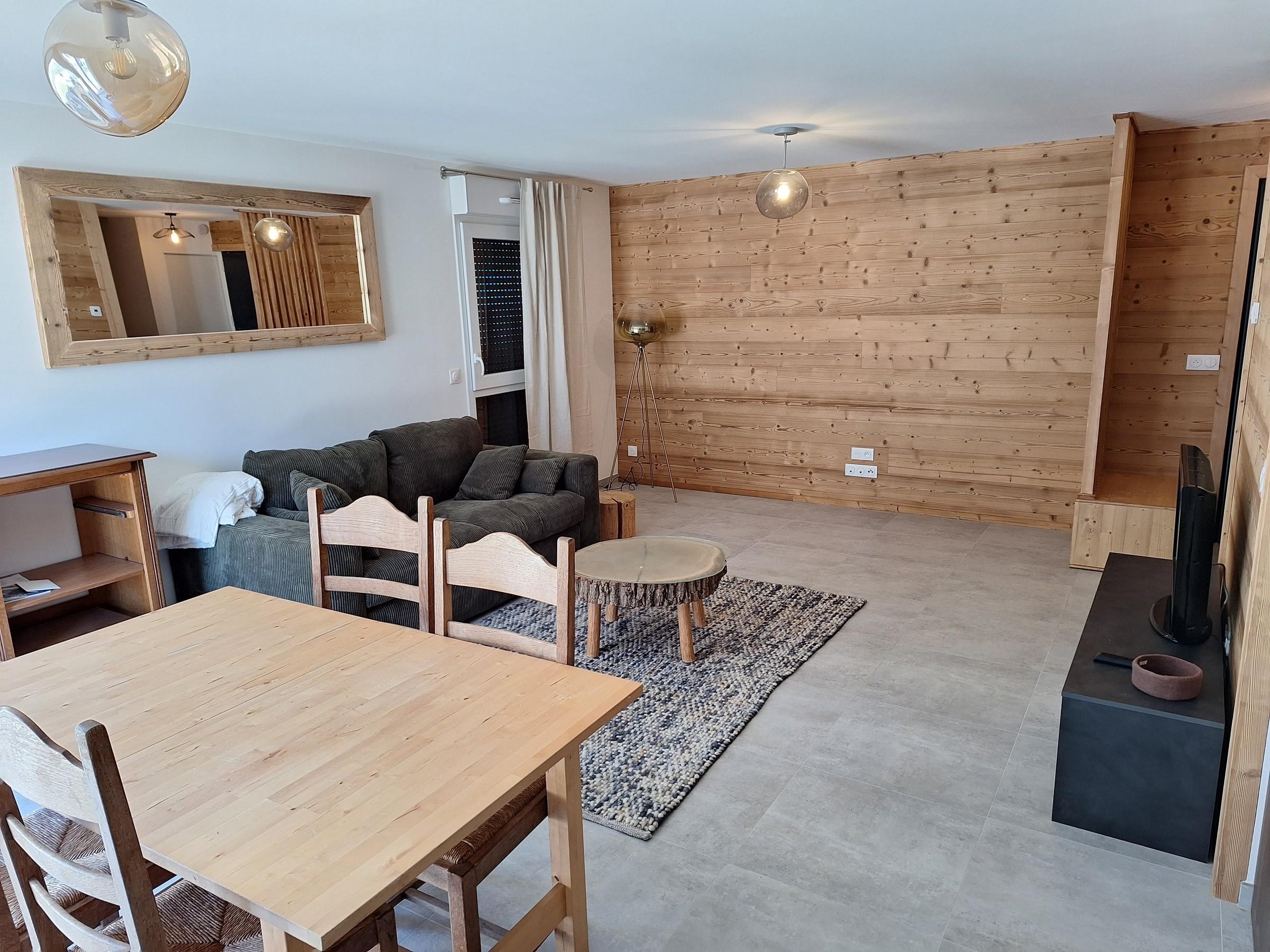 Salon rénové avec murs habillés de bois, par Aravis Menuiserie
