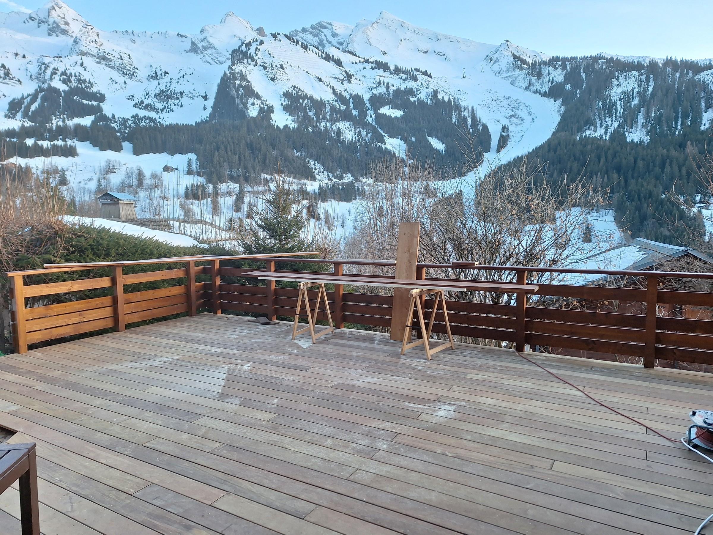 Terrasse en bois face aux montagnes enneigées, réalisée par Aravis Menuiserie